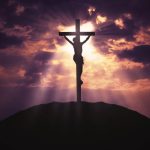 Christian cross on hill at sunrise
